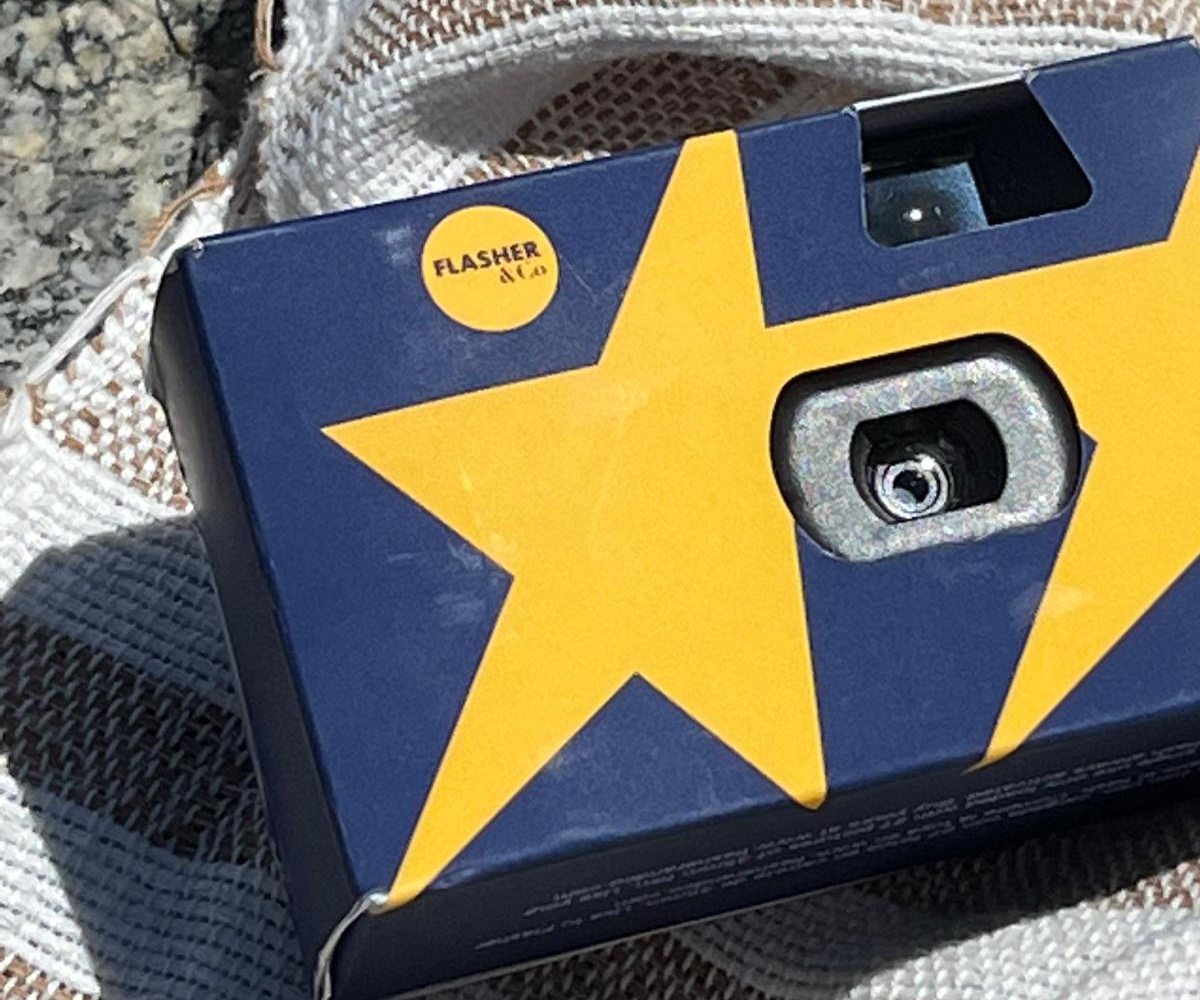 Cámara de un solo uso personalizada, con una estrella amarilla sobre fondo azul y el logo de Flasher&Co